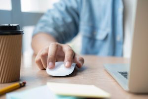 Close-up of a hand using a computer mouse on a desk, symbolizing secure and seamless digital workflows.
